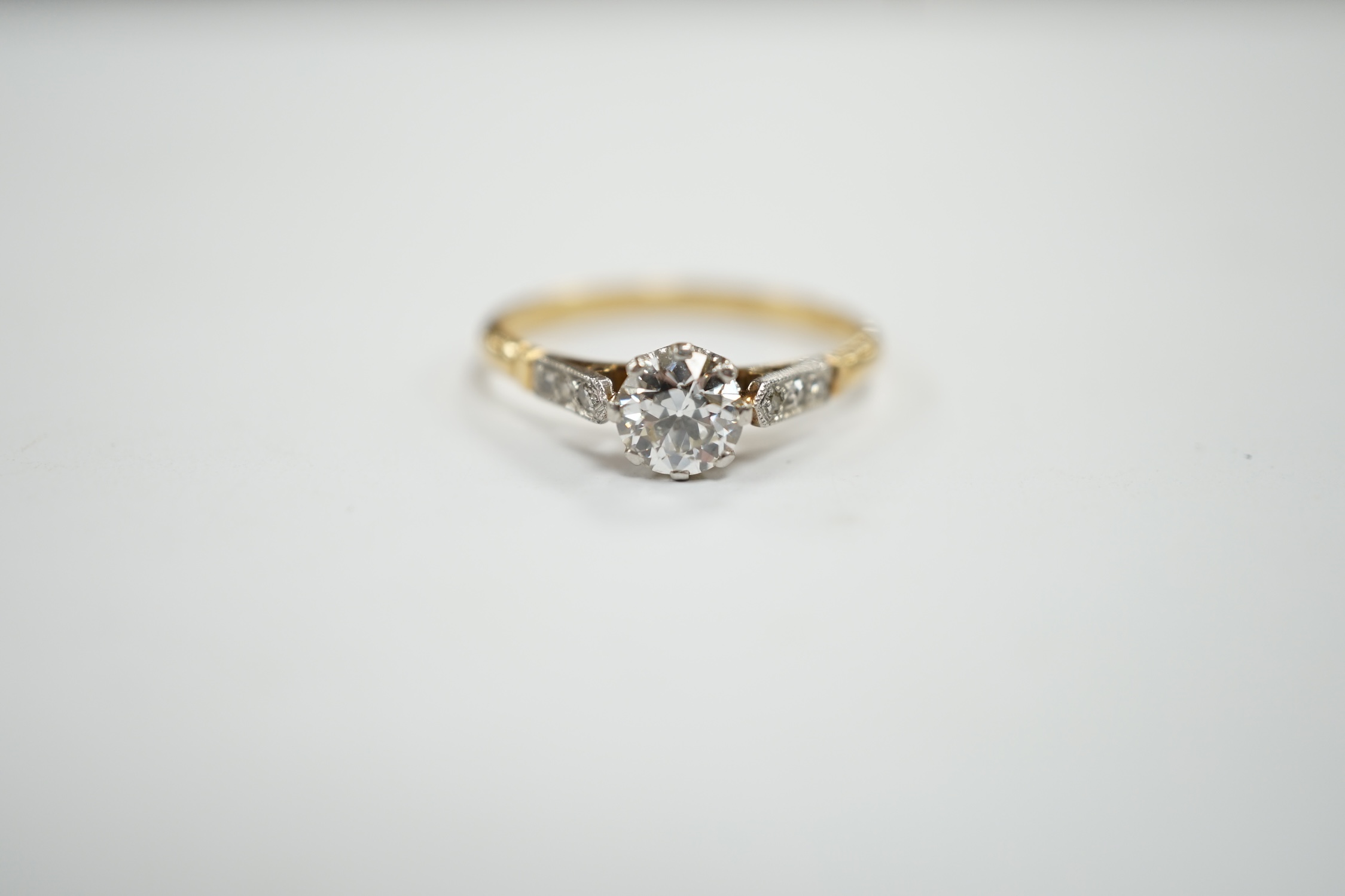 An early 20th century yellow metal and single stone diamond set ring, with diamond chip set shoulders, size N/O, gross weight 2.4 grams.